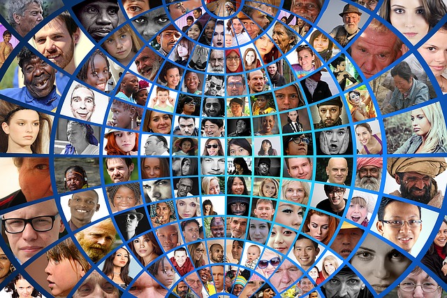 Photo of flat globe, divided into small squares with a different person's face in each, of different races