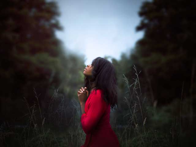 Woman in red dress looking up at the sky, praying