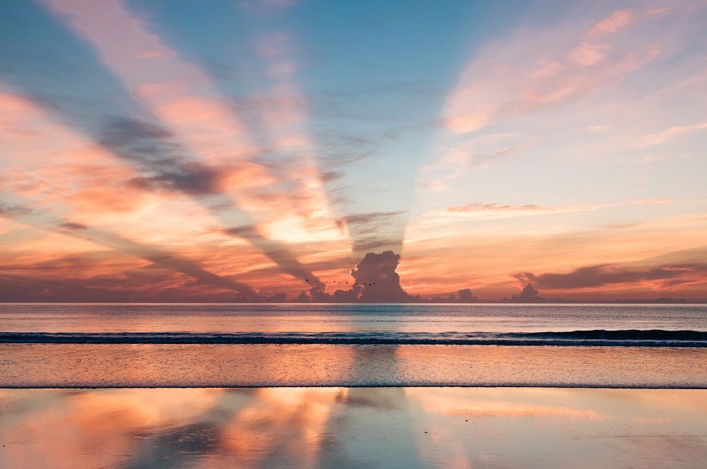 Orange, cloudy sunset over body of water